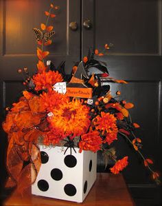 a vase filled with orange flowers sitting on top of a wooden table next to a black door