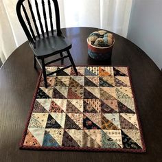 a wooden chair sitting next to a table with a quilt on it