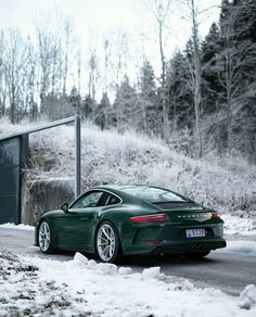 a green sports car parked on the side of a road covered in snow and ice