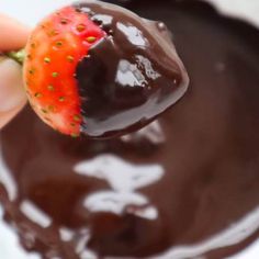 a hand holding a chocolate covered strawberry