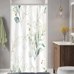 a white shower curtain with green leaves on it