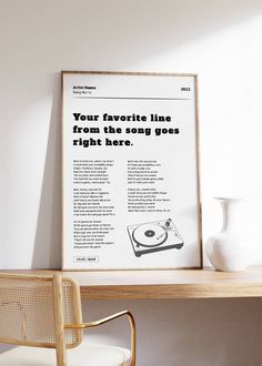 a record player sitting on top of a wooden table next to a white vase and chair