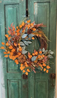 a green door with a wreath hanging on it's side and an orange flower in the middle