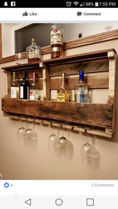 a wooden shelf with wine glasses and liquor bottles hanging on it's sides, in front of a mirror