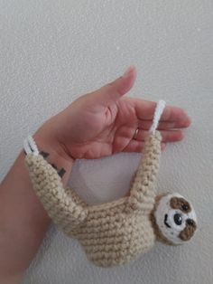 a hand holding a small stuffed animal in the shape of a slotty hanging from it's side