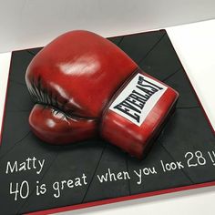 a cake made to look like a red boxing glove on top of a black mat