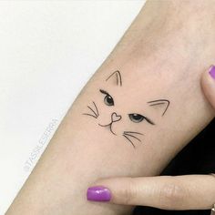 a woman's hand with a cat tattoo on her left wrist and the other arm