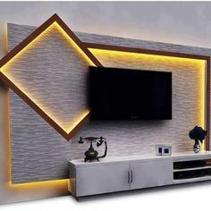 a tv mounted to the side of a wall next to a white entertainment center with lights on it