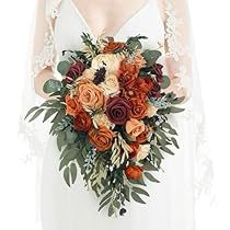 a woman in a white dress holding a bouquet of orange and red flowers on her wedding day