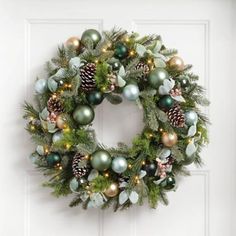 a christmas wreath hanging on the front door with pine cones, evergreen and other ornaments