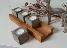 three candles are sitting on a wooden stand next to some deer figurines and a branch with berries