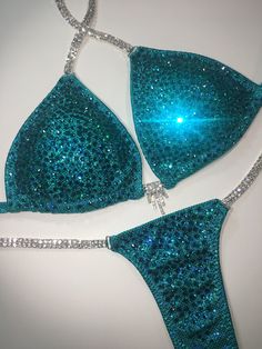 two pieces of blue glitter bikinisuits with silver chains on the bottom and side