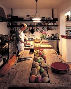 a woman standing in a kitchen preparing food on top of a wooden counter next to pots and pans