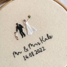 a close up of a wedding embroidered on a piece of cloth with a couple holding hands