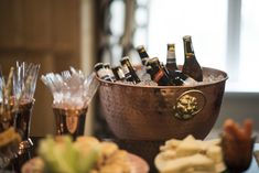 there are many bottles of beer in the bowl on the table and glasses next to it