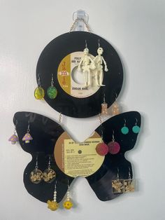 an old record with earrings hanging from it's sides on a wall next to a clock