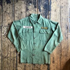 "A rare and beautiful vintage 1961 Vietnam era OG-107 P64 shirt, name patch \"Schaefer\" about right breast pocket and \"US Army\" about left breast pocket. Six button original closure. Two chevrons on both left and right arms.  Size: Medium  Wear: Very good condition, nice fade and light patina. Pit to pit: 21 Inch  Collar to hem (on back of item): 28 Inch   shoulder to shoulder 18.5 Inch Arm: 21 Inch  We lovingly hand pick every vintage item for its age, uniqueness, coolness and style.  Hope you like our finds. All of our items are vintage and may show signs of previous wear. Any significant wear, damage or marks will be photographed however we love a bit sunfade and a vintage repair, they just add character for us. We have a store in Brighton and you can also follow us on Instagram to k Vintage Button-up Shirt With Patch Pockets, Vintage Long Sleeve Top With Patch Pockets, Vintage Cotton Shirt With Pockets, Vintage Green Tops With Pockets, Green Vintage Tops With Pockets, Army Fatigue, Name Patches, Wool Shirt, Quality Hats