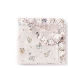 a blanket with animals on it and ruffles around the edges is folded in front of a white background