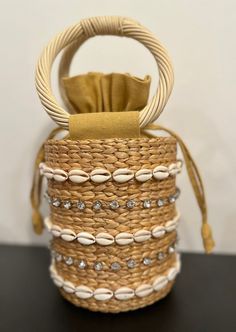 Our Leah Bag is our new favorite mini bag for spring and summer! With shell and stone embellished detail on a simple straw bag with round handles, this handheld adds style and personality to any outfit.  Material: 100% straw, 100% Cotton Lining, Shell and Stone Detail Spot Clean with Damp Cloth Summer Beach Bags Made Of Shell, Elegant Bucket Bag With Braided Handles For Beach, Natural Beach Bag With Pearl Handle, Chic Straw Bag With Pearl Handle For Beach, Chic Straw Beach Bag With Pearl Handle, Summer Straw Bag With Pearl Handle In Natural Color, Chic Straw Bag With Pearl Handle For Vacation, Chic Beach Straw Bag With Pearl Handle, Elegant Straw Bag With Handles For Beach