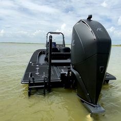 a black boat is in the water with it's front end up and its engine out