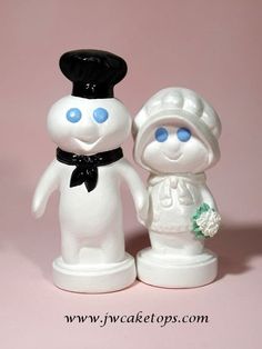 a couple of white figurines standing next to each other on a pink background