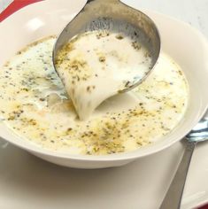 a white plate topped with soup and a spoon