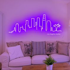 a living room filled with furniture and a purple neon sign above the couch in front of it