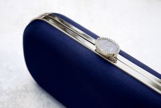 The Navy Bella Clutch is a custom designer clutch, and a timeless choice for an elegant wedding handbag. We’ve found your something blue… Your bridal purse. The Navy Bella Clutch is the perfect option for an evening wedding, as the duchess satin feels luxurious and sensible, without sacrificing style. Perhaps you’re celebrating on the New England coast at a chic hotel or private estate, complete your look with a stylish and elevated custom purse that you’ll love for years to come. The Bella Clut Elegant Rectangular Evening Bag For Events, Elegant Evening Bag For Events, Elegant Rectangular Clutch For Wedding Guest, Elegant Formal Clutch, Classic Clutch Evening Bag, Timeless Rectangular Clutch For Parties, Elegant Blue Bag With Pearl Handle, Timeless Rectangular Clutch For Party, Modern Clutch With Detachable Handle For Formal Events