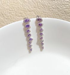 Amethyst Purple Earrings featuring semi precious purple stones and cz diamonds. Perfect for any special occasion look or a wedding bridesmaid look. These Purple Dangle Earrings surely add a touch of super luxury in your entire look. Also a perfect gift for her or gift for mom. *𝐏𝐑𝐎𝐃𝐔𝐂𝐓 𝐃𝐄𝐓𝐀𝐈𝐋* * 𝐌𝐚𝐭𝐞𝐫𝐢𝐚𝐥: Brass * 𝐏𝐥𝐚𝐭𝐢𝐧𝐠: White Rhodium Plated * 𝐒𝐭𝐨𝐧𝐞: AAA-quality CZ diamond. *𝐃𝐈𝐌𝐄𝐍𝐒𝐈𝐎𝐍𝐒* * 𝐖𝐞𝐢𝐠𝐡𝐭: 3 gm each * 𝐋𝐞𝐧𝐠𝐭𝐡: 5 cm * 𝐖𝐢𝐝𝐭𝐡:  1 cm Drop Crystal Earrings With Gemstones, Dangle Earrings With Gemstone Accents In Cubic Zirconia, Dangle Earrings With Cubic Zirconia And Gemstone Accents, Gemstone Cubic Zirconia Drop Earrings, Elegant Purple Cubic Zirconia Crystal Earrings, Dangle Earrings With Gemstone Accents And Cubic Zirconia, Cubic Zirconia Gemstone Drop Earrings, Purple Cubic Zirconia Jewelry With Sparkling Stones, Purple Cubic Zirconia Earrings