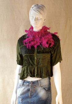 a mannequin wearing a green top with pink feathers on it's chest