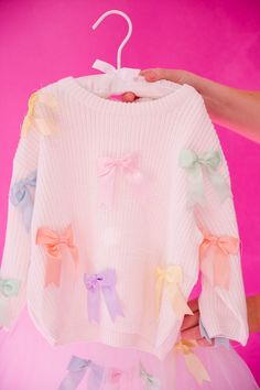 Hop into spring with our MINI KIDS PASTEL BOWS SWEATER! This cozy white waffle sweater features adorable pastel bows on the pullover, perfect for Easter or any day. Get your little one ready to bloom in style! This is a made-to-order item. All customized orders are currently shipping within 14 business days. To receive item quicker, expedited shipping is available at checkout. Playful White Winter Sweater, Long Sleeve Sweater With Bow For Spring, Spring Long Sleeve Sweater With Bow, Playful White Sweater For Spring, Pastel Bows, Waffle Sweater, Bow Sweater, Little One, In Style