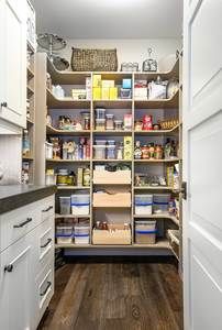 an organized pantry with white cabinets and wood flooring is seen in this image from the inside