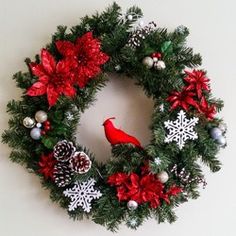 a christmas wreath with red and silver decorations on it, hanging from the wall next to a white wall