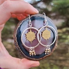 Inspired by the eclipse, these large sterling silver hammered hoops feature a hand cut brass sun motif. Accenting the hoops are brass bead dangles. The custom swirly ear wires add interest and a unique twist. The mixed metals are striking paired together. Wearable all summer long! Made to order - approx. 2 inches total in length. Sun Motif, Bead Dangles, Sun Flare, The Eclipse, Hammered Silver, Mixed Metals, Beaded Dangles, Ear Wires, Hoop Earrings