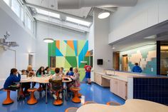 a group of people sitting around a table in a room with blue and orange flooring