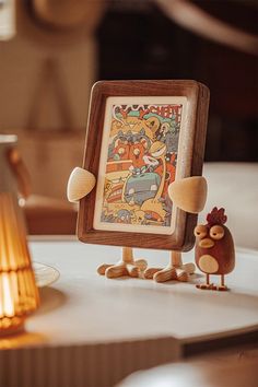 an image of a wooden frame on top of a table with a rooster figurine next to it