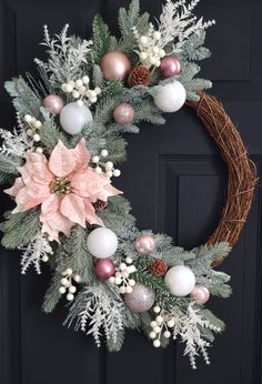 a christmas wreath with pink and white ornaments hanging on the front door's black door