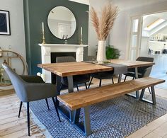 a dining room table with two chairs and a bench in front of the fire place