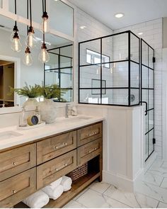 a bathroom with two sinks, mirrors and lights on the wall next to each other