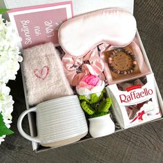 an open box with items inside it on a table next to flowers and other things