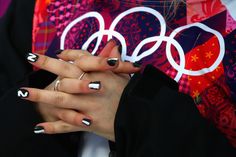 a woman with black and white nail polish holding her hands in front of the olympic rings