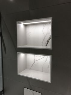 two white shelves in the corner of a bathroom