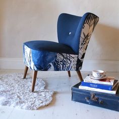 a blue chair sitting next to a pile of books on top of a white rug