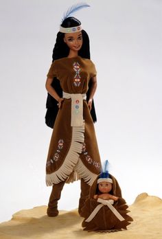 the doll is standing next to her mother in native dress and headdress on