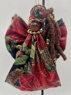 a cloth angel ornament hanging on a pole with a red and green scarf around it's neck