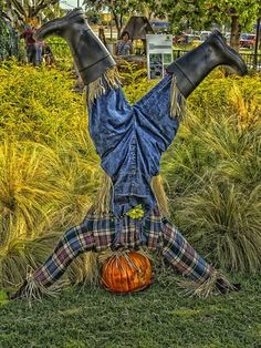 a scarecrow laying on its back in the grass with his legs spread out and head down