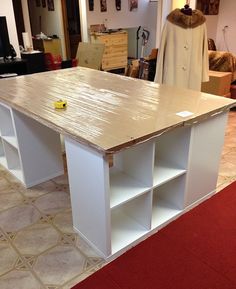 a kitchen island made out of plywood and white cabinets in a room with red carpet