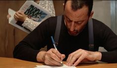 a man sitting at a table writing on paper