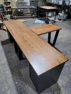 a wooden bench sitting on top of a floor next to other tables in a room