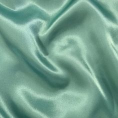 a close up view of a green satin fabric with very soft folds and lines on it